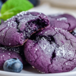 Vibrant blueberry cookies with a soft, chewy texture, sprinkled with sugar and served with fresh blueberries and a mint leaf garnish