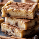 A stack of soft, chewy Snickerdoodle Blondies with a golden-brown crust and a gooey cinnamon center.